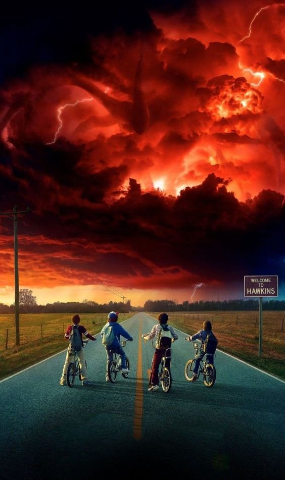 Four kids on bikes look at a creepy tentacled storm in the distance