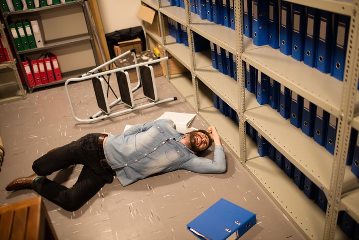 High angle view of fallen businessman and file in storage room