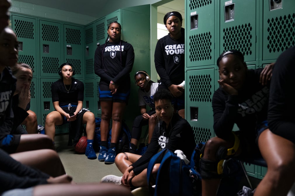 A team of young women athletes in their locker room before a match, serious and sombre and attentive