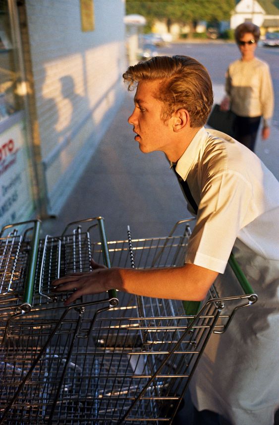 Teenager pushes trolleys into a supermarket, warm afternoon light