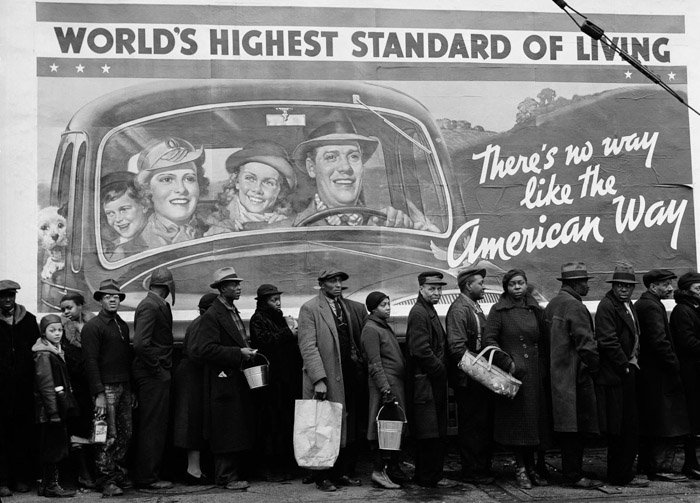 Photograph taken by Margaret Bourke-White after the 1937 Louisville Flood. The photograph depicts African-Americans lined up for flood relief. Behind them is a billboard depicting a smiling white nuclear family riding in their car. The billboard reads "World's highest standard of living. There's no way like the American Way".