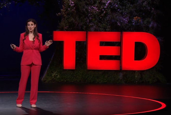 Ilissa Ocko stands on the TED stage, speaking