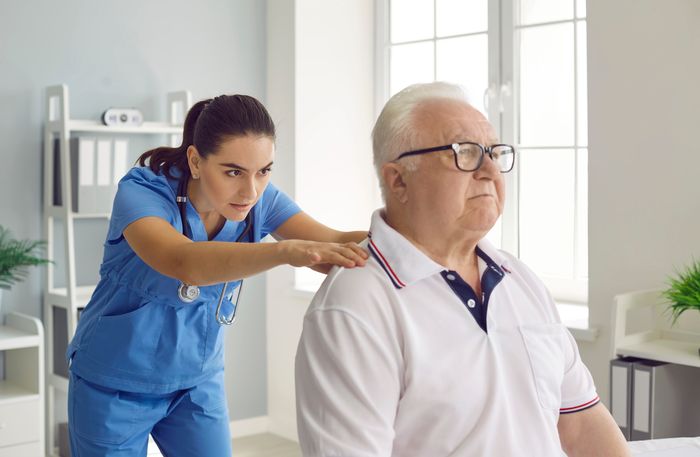 Chiropractor or physiotherapist examining a senior male patient